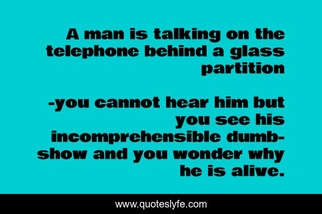 A man is talking on the telephone behind a glass partition